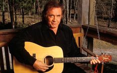 a man sitting on a bench holding a guitar