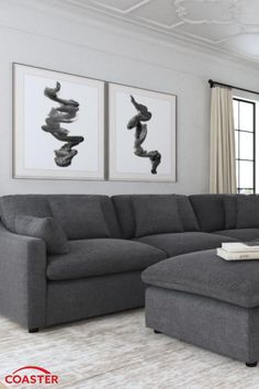 a living room with gray couches and pictures on the wall above it, along with a large ottoman