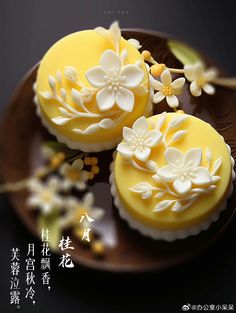 two yellow cupcakes decorated with white flowers on a brown plate