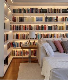 a bed sitting in front of a book shelf filled with lots of books on top of it