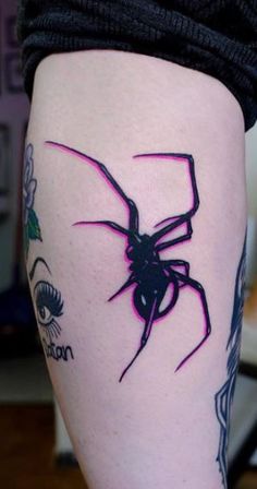 a woman's leg with a spider tattoo on the side of her thigh and eyeliners