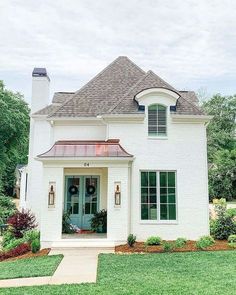 a white brick house with green shutters on the front door and windows in the side