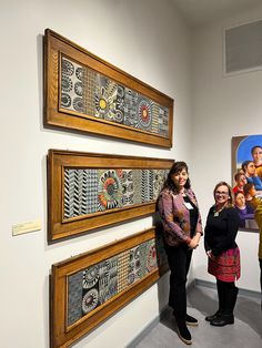 three women standing next to each other in front of artwork