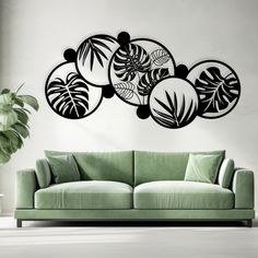 a green couch sitting in front of a wall with black and white designs on it