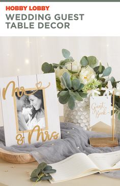 wedding guest table decor with white flowers and greenery in vases next to an open book