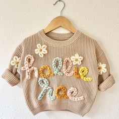 a knitted sweater with the word love spelled out in crochet and flowers