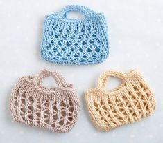 three crocheted purses sitting on top of a white table next to each other