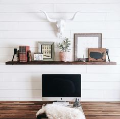 a desk with a computer on top of it next to a cow's head