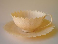 a white bowl sitting on top of a table next to a paper flower shaped object