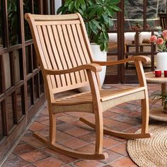 a wooden rocking chair sitting on top of a patio next to a potted plant