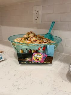 a bowl full of food sitting on top of a counter next to a box of cereal