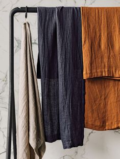 three towels hanging on a rack in front of a marble wall with black and orange colors