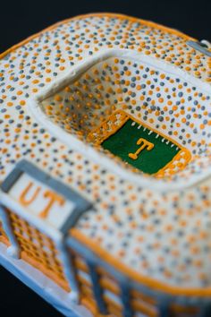 an orange and white dotted cake with the letter t in it's center, sitting on a black surface