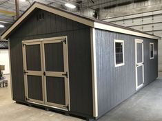 a storage shed with two doors and windows on the side, in a warehouse building