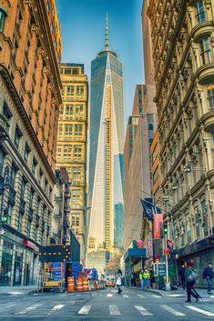 an empty city street with tall buildings and people walking on the sidewalk in front of it