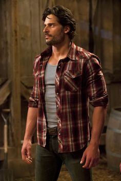 a man standing in front of a barn door wearing a red and white plaid shirt