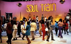 a group of people standing in front of a neon sign that says soul train on it