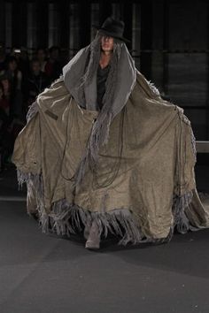 a woman walking down a runway wearing a cape