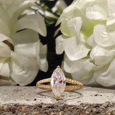 a close up of a ring on a rock with flowers in the backgroud