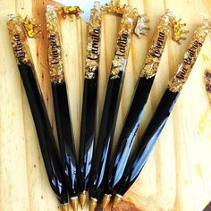 five black and gold colored toothbrushes sitting on top of a wooden cutting board