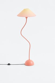 a pink lamp on a white surface with a cord running through it and a light bulb plugged in