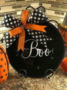 a black plate with polka dots and a bow on it sitting next to pumpkins