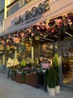 a flower shop with flowers in the window and on the side of the building that says la rose