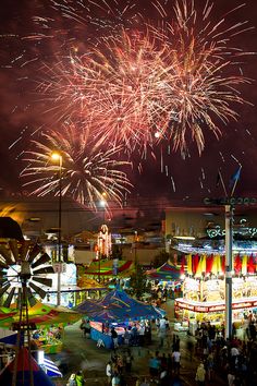 fireworks are lit up in the night sky above an amusement park with rides and carousels