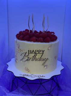 a birthday cake with raspberries on top