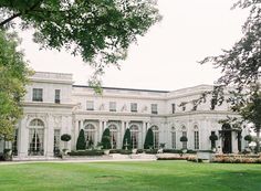 a large white building with lots of windows on the front and side of it, surrounded by lush green grass