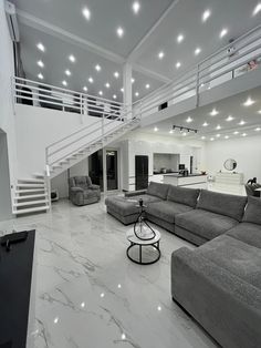 a living room filled with lots of furniture and a staircase leading up to the second floor