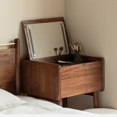 a wooden dresser with mirror and pen holders on it's sides next to a bed