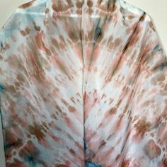 a tie - dyed shirt is shown on a white tablecloth with red, blue and brown colors