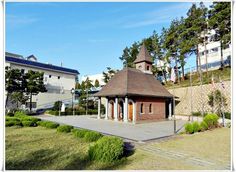 a small building with a steeple on top in the middle of a grassy area