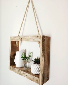 a wooden shelf with two vases and plants hanging from it's sides on a white wall