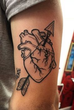 a man's arm with a heart and arrow tattoo on it