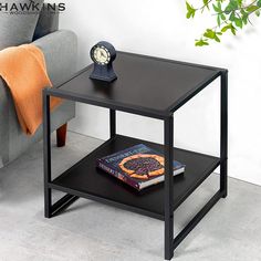 a black table with a book on it next to a gray couch and a plant