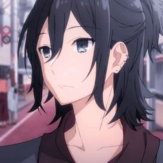 an anime character with black hair and blue eyes standing in front of a train station