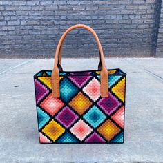 a colorful handbag sitting on top of a sidewalk