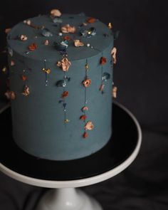 a blue cake with flowers on it sitting on a black and white plate in front of a dark background