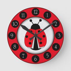 a red clock with black numbers and a ladybug on the front is shown