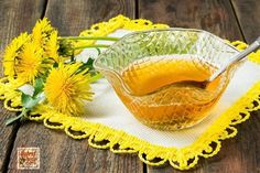 a glass bowl filled with liquid on top of a table next to dandelions