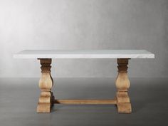 a white marble table with wooden legs on a grey surface in front of a gray wall