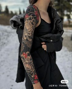 a woman with tattoos on her arms and arm sleeve is standing in the snow, wearing a black dress