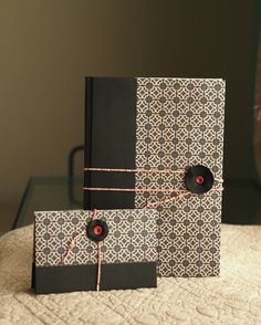 two black and white cards with red buttons on them sitting on top of a bed