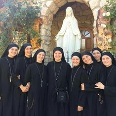 the women are posing in front of the statue