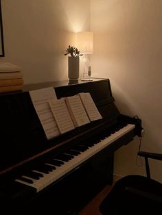 a black piano with sheet music sitting on it's stand next to a lamp