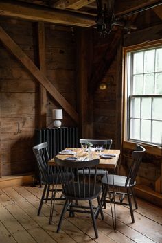 a dining room table and chairs in front of a window with wood paneled walls