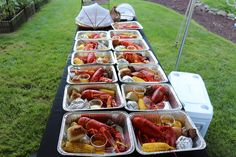 lobsters and corn on the cob are served in trays at an outdoor party