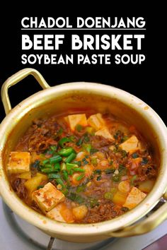 a bowl filled with beef and vegetable soup on top of a table next to a spoon